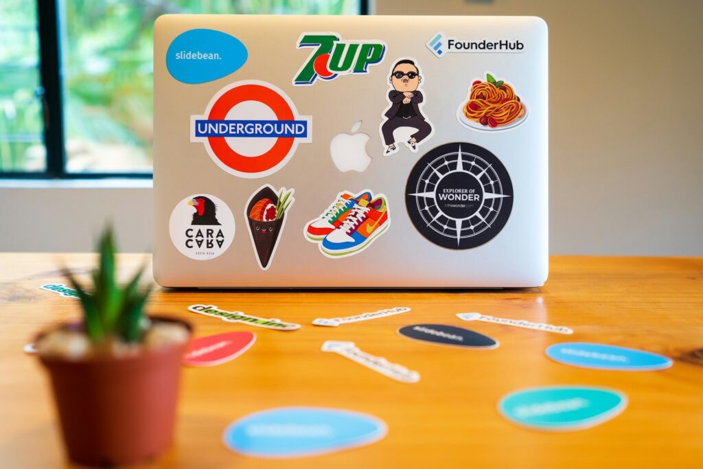 MacBook Air posé sur un bureau. Dos de l'ordinateur avec des stickers colorés de marque et de références à la pop culture.
Co-branding AVICOM'