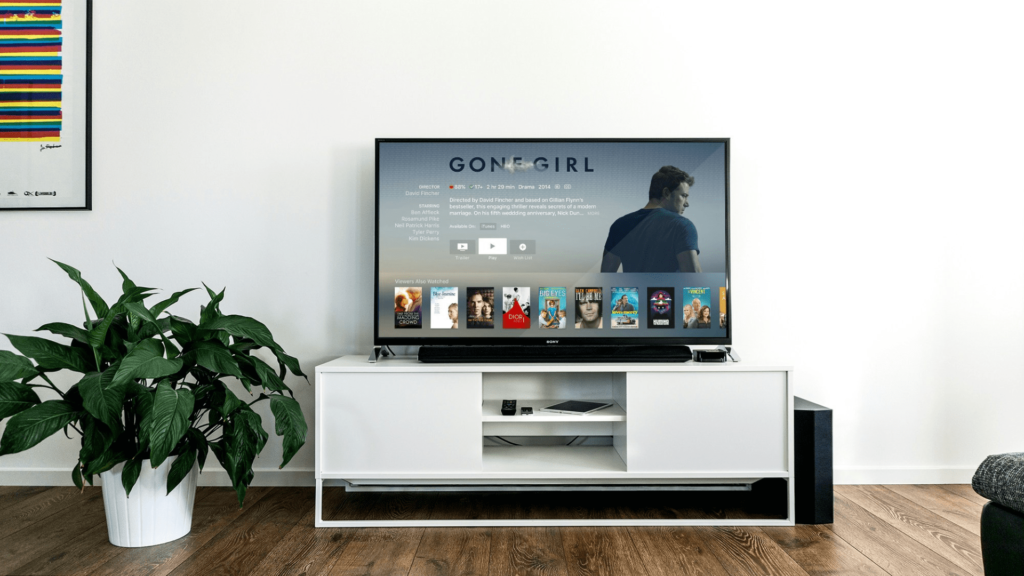 Télévision affichant un film avec un meuble télé bas blanc. décoration naturelle et épurée.